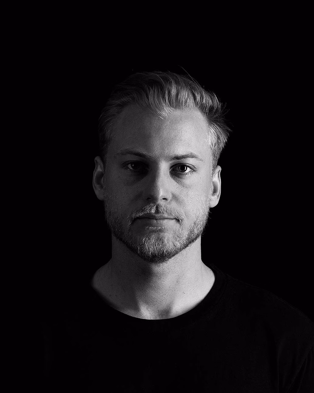 Marvin Wolter blickt ernst in die Kamera. Das Porträt ist in Schwarz-Weiß gehalten, mit einem dunklen Hintergrund.